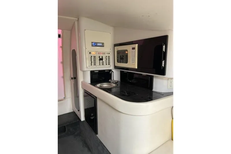 Slide: The Image of 2002 Donzi 38 Daytona interior with kitchenette, featuring sink, microwave, and control panel. - 17