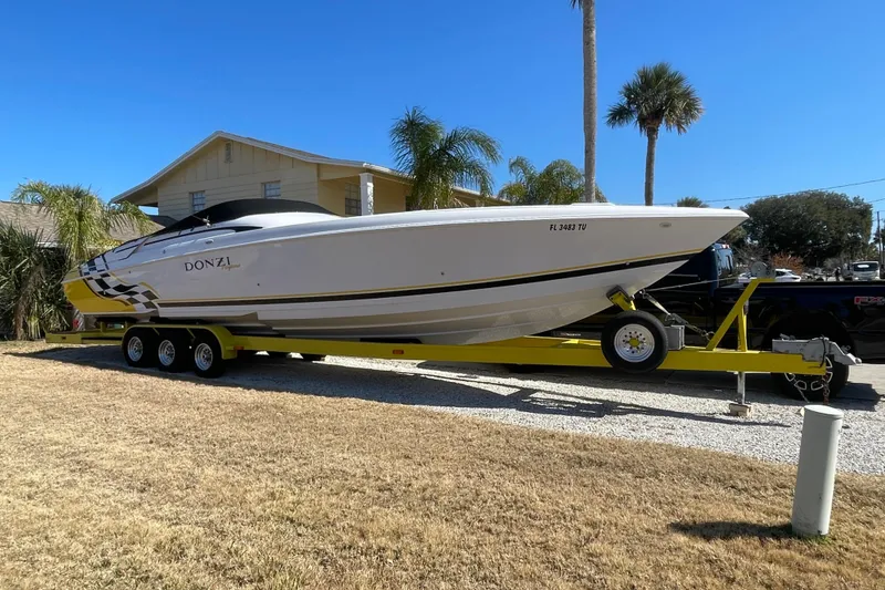 Slide: The Image of 2002 Donzi 38 Daytona boat on trailer, parked in a sunny residential area. - 24
