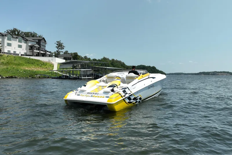 Slide: The Image of 2002 Donzi 38 Daytona speedboat cruising on a lake near waterfront homes. - 3