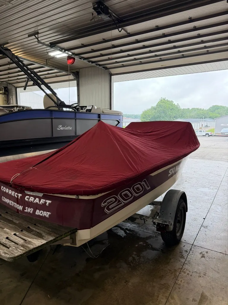Slide: The Image of A 1987 Correct Craft Ski Nautique 2001 with a red cover in a storage facility. - 26