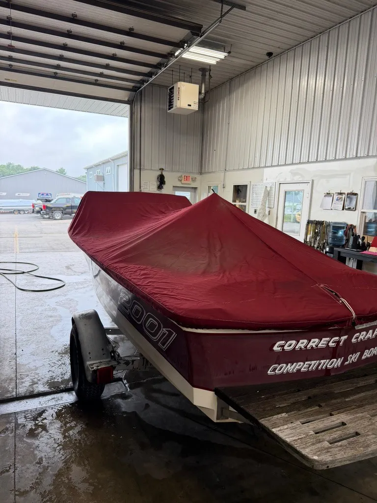 Slide: The Image of A 1987 Correct Craft Ski Nautique 2001 with a red cover is in a workshop. - 25