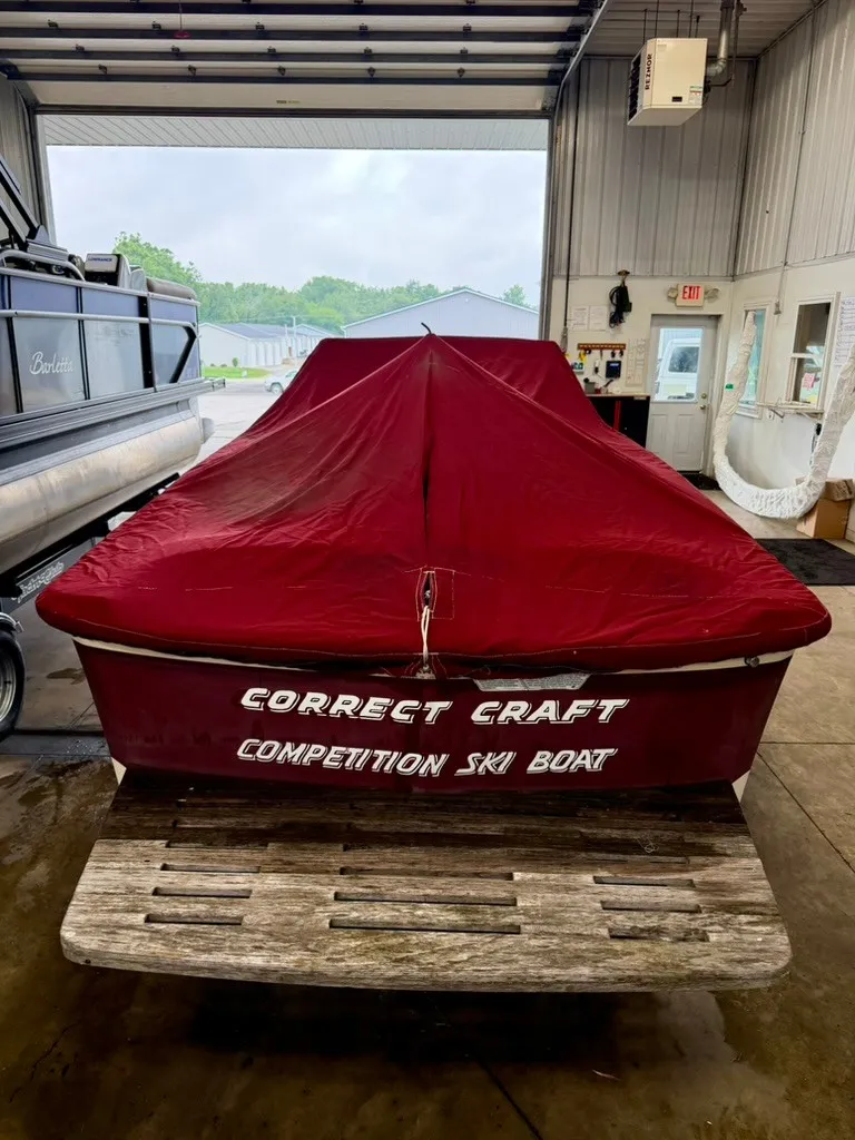 Slide: The Image of A 1987 Correct Craft Ski Nautique 2001 with a red cover in a warehouse. - 24