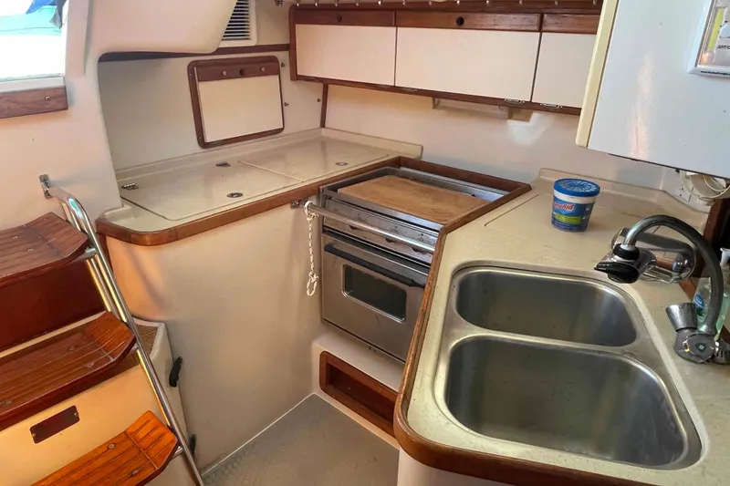 Slide: The Image of Catalina 320 yacht kitchen with dual sinks, stove, and wooden accents. - 25
