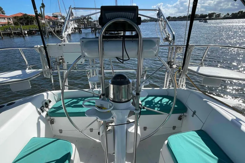 Slide: The Image of Cockpit view of a Catalina 320 sailboat with teal cushions and marina backdrop. - 87