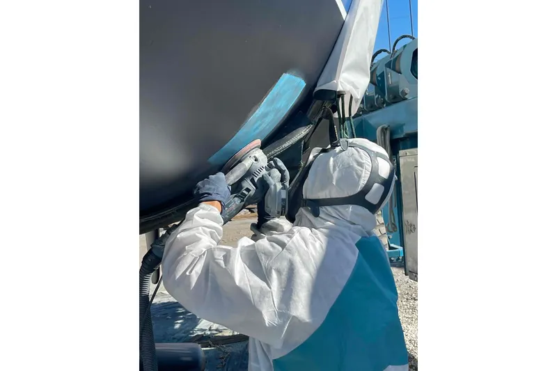 Slide: The Image of Person sanding a Catalina 320 boat hull, wearing protective gear. - 39