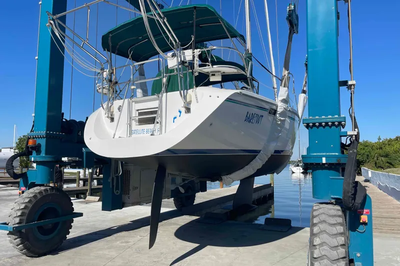 Slide: The Image of Catalina 320 sailboat lifted by a blue hoist at a marina. - 51