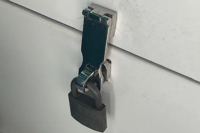 Slide: The Image of Padlock securing a latch on a white surface, Catalina 320, 1995 model. - 83