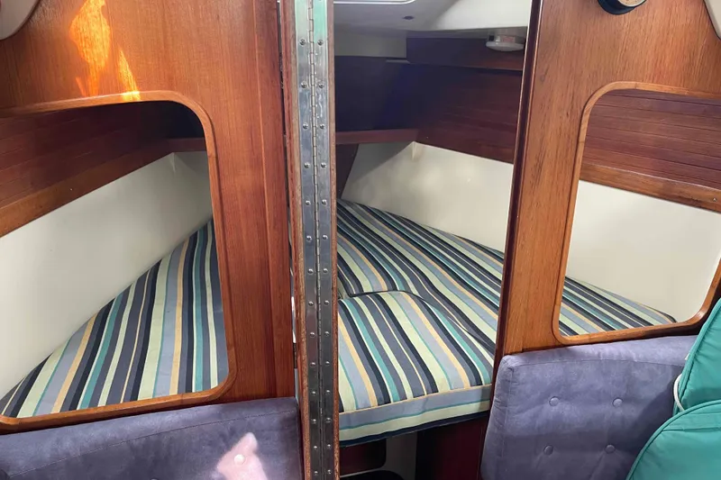 Slide: The Image of Catalina 320 sailboat interior with striped bedding and wooden finish. - 105