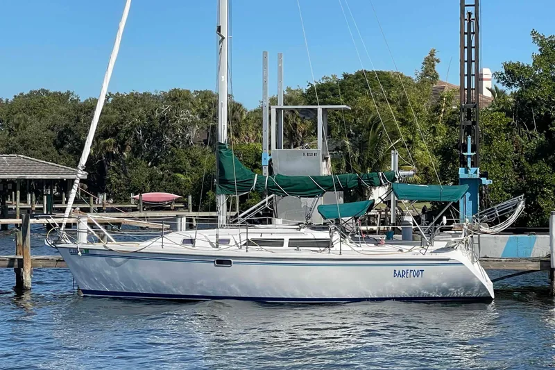Slide: The Image of Sailboat Catalina 320 docked with green covers, named "Barefoot." - 57