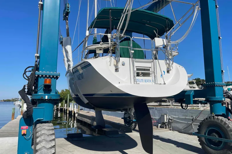 Slide: The Image of Catalina 320 sailboat from 1995 being lifted by a boat hoist at a marina. - 53