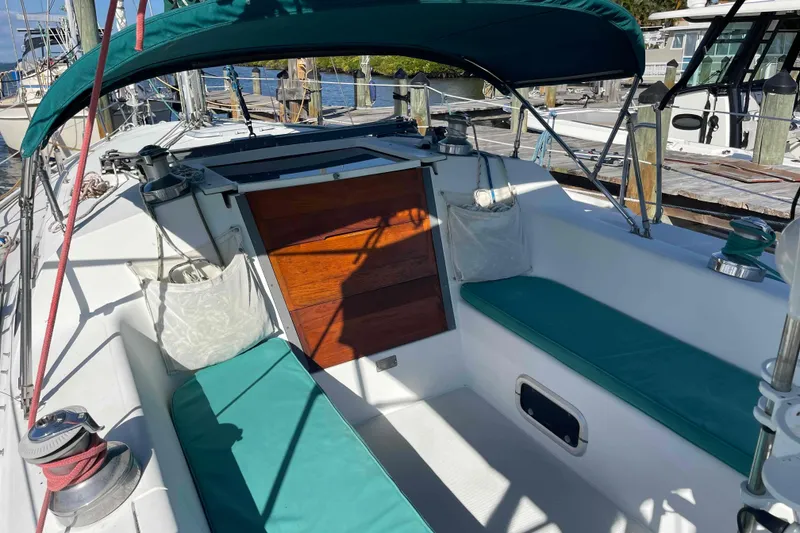 Slide: The Image of Catalina 320 sailboat cockpit with teal cushions and wooden hatch, docked at marina. - 86