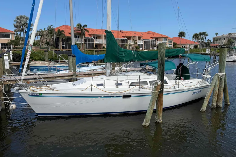 The Image of Sailboat Catalina 320, 1995 model, docked at marina with green covers. - 0