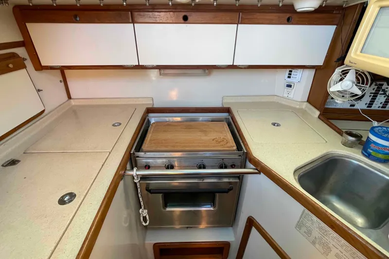 Slide: The Image of Catalina 320 yacht kitchen with stove, sink, and storage cabinets. - 97