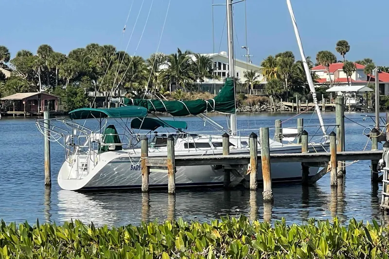 Slide: The Image of Sailboat Catalina 320 docked by a scenic waterfront with palm trees. - 58