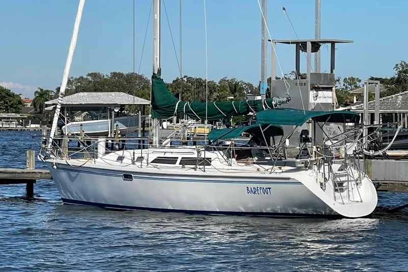 Slide: The Image of Catalina 320 sailboat docked with green covers, named "Barefoot." - 56