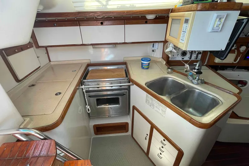 Slide: The Image of Catalina 320 yacht kitchen with stove, double sink, and microwave. - 16