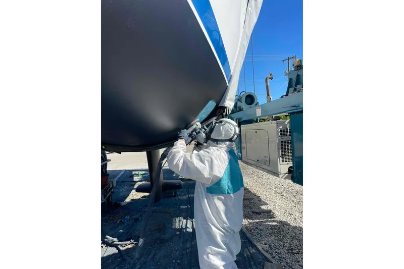 Slide: The Image of Person in protective gear working on Catalina 320 boat hull. - 38