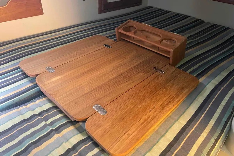 Slide: The Image of Wooden folding table on striped bedding in a 1995 Catalina 320 boat cabin. - 88