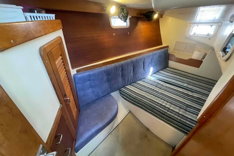 Slide: The Image of Cozy cabin interior of 1995 Catalina 320 sailboat with striped bedding and wooden accents. - 14