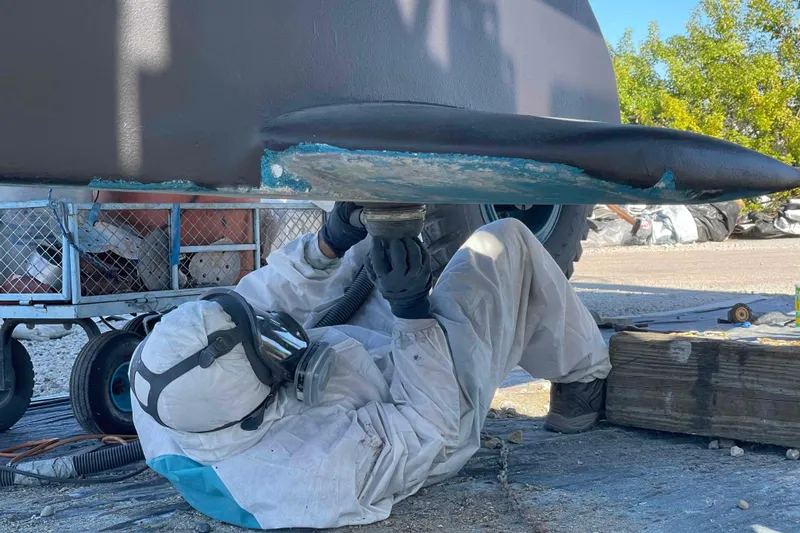 Slide: The Image of Person in protective gear working on Catalina 320 boat hull maintenance. - 40