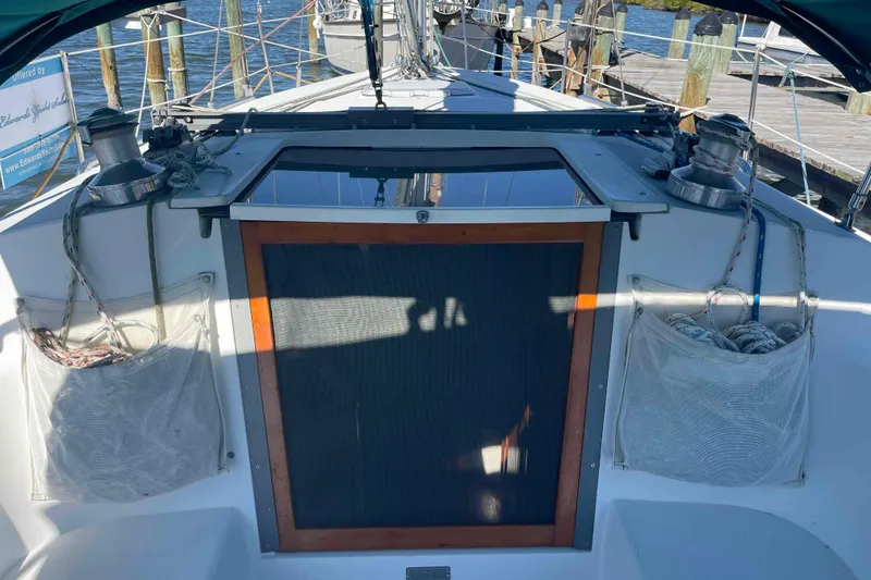 Slide: The Image of 1995 Catalina 320 sailboat cockpit with winches and rope storage, docked at marina. - 82