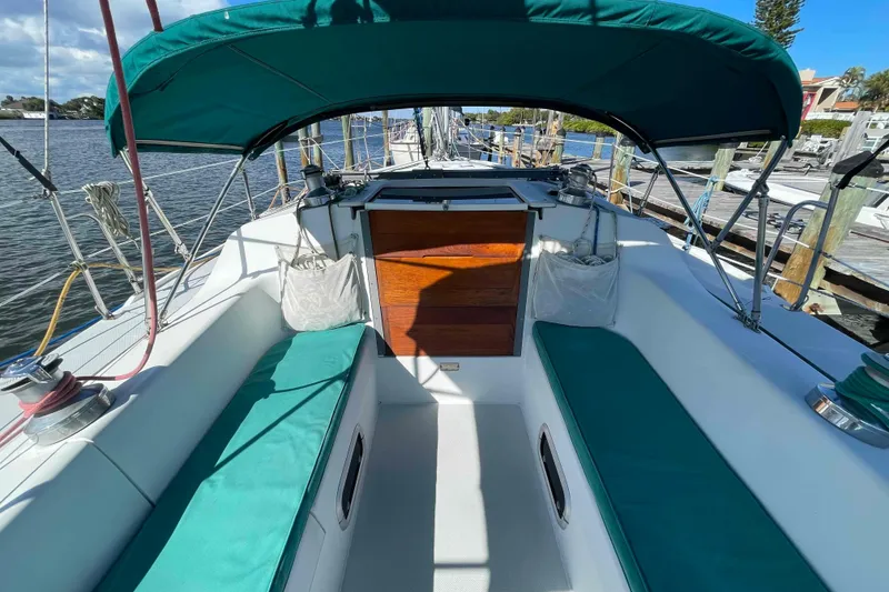 Slide: The Image of Catalina 320 sailboat cockpit with green cushions and canopy, docked by the water. - 79
