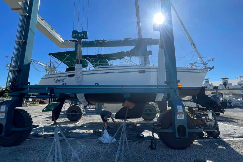 Slide: The Image of Catalina 320 sailboat in dry dock, undergoing maintenance under bright sunlight. - 48