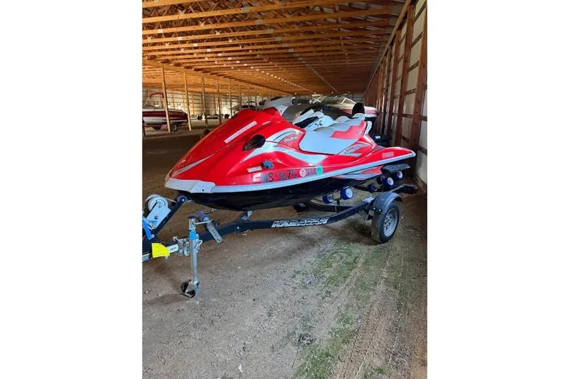 The Image of Red 2006 Yamaha VX110 Deluxe jet ski on trailer in storage facility. - 1