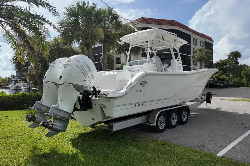 Slide: The Image of 2023 Sea Fox 328 Commander boat on trailer, parked near palm trees and buildings. - 4