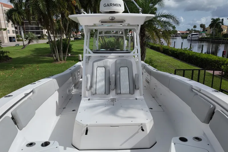 Slide: The Image of 2023 Sea Fox 328 Commander boat interior with seating, docked near palm trees and waterway. - 9