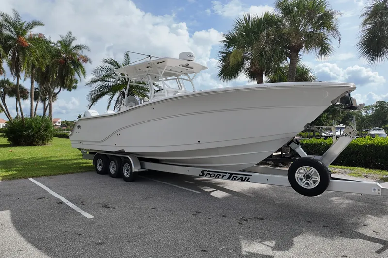The Image of 2023 Sea Fox 328 Commander boat on trailer, parked near palm trees. - 1