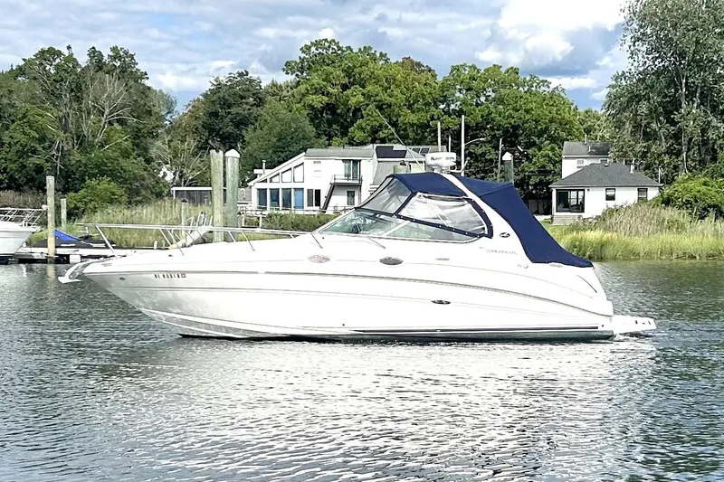 The Image of 2006 Sea Ray Sundancer 280 boat on a calm lake with houses in the background. - 0