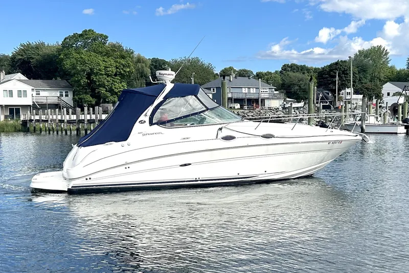Slide: The Image of 2006 Sea Ray Sundancer 280 boat on calm water, with blue canopy and scenic background. - 7
