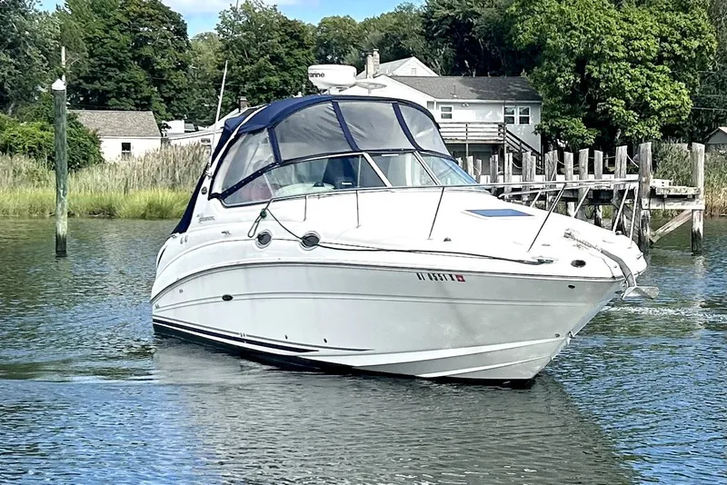 Slide: The Image of 2006 Sea Ray Sundancer 280 boat cruising near a dock with lush greenery. - 4