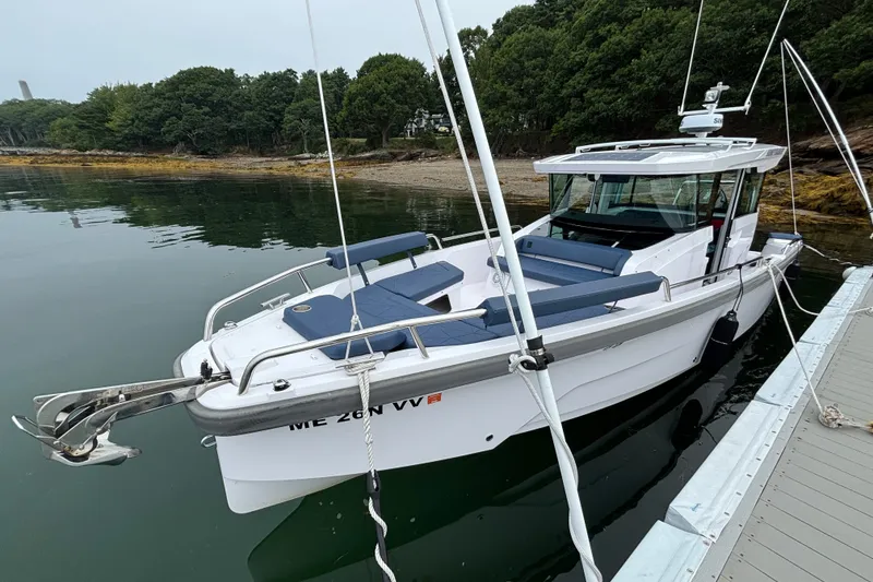 Slide: The Image of 2025 Axopar 29 XC Cross Cabin boat docked by a serene shoreline. - 1