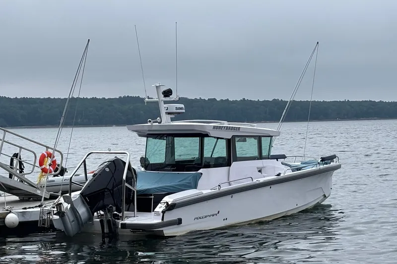 Slide: The Image of 2025 Axopar 29 XC Cross Cabin boat docked on a calm lake. - 4