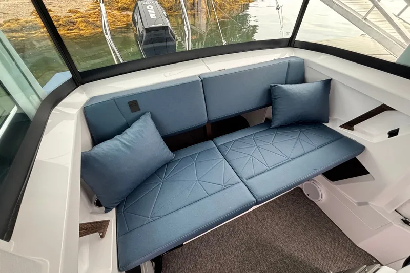 Slide: The Image of 2025 Axopar 29 XC Cross Cabin interior with blue cushioned seating and pillows. - 30