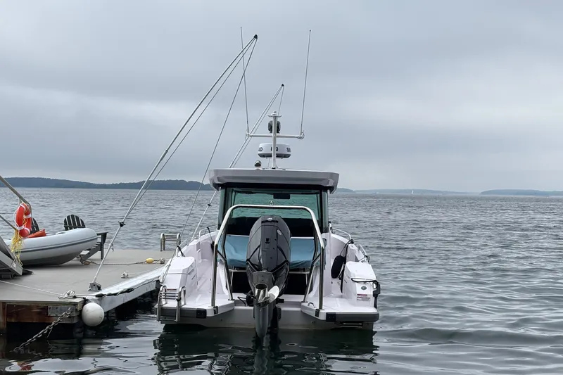 Slide: The Image of 2025 Axopar 29 XC Cross Cabin boat docked on a calm, overcast day. - 9