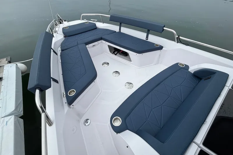 Slide: The Image of 2025 Axopar 29 XC Cross Cabin boat interior with blue cushioned seating and stainless steel railings. - 40
