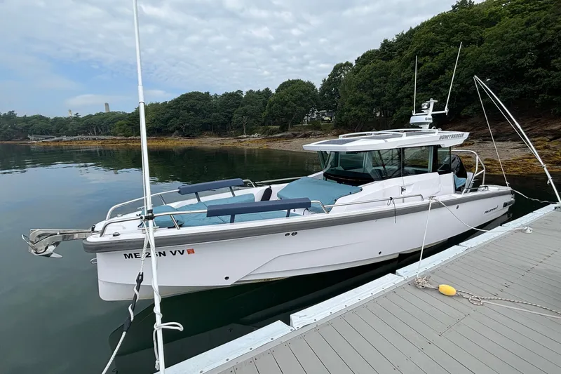 Slide: The Image of 2025 Axopar 29 XC Cross Cabin boat docked on calm water, surrounded by lush greenery. - 6