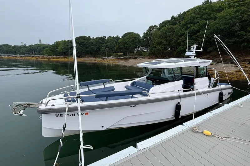 Slide: The Image of 2025 Axopar 29 XC Cross Cabin boat docked by a serene, wooded shoreline. - 2