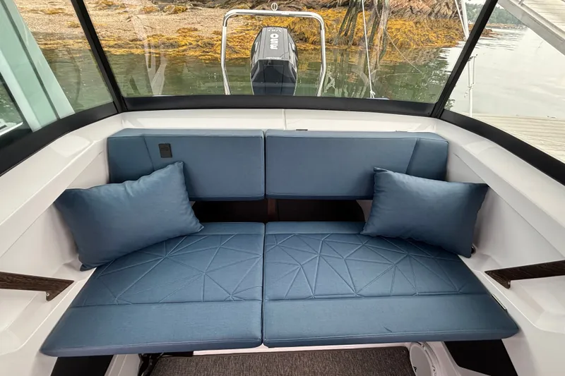 Slide: The Image of 2025 Axopar 29 XC Cross Cabin interior with blue cushioned seating and pillows. - 31