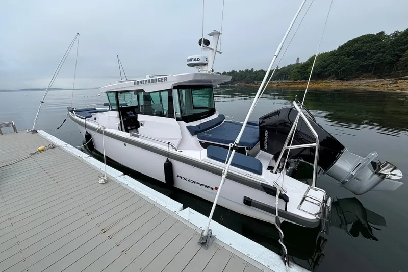 Slide: The Image of 2025 Axopar 29 XC Cross Cabin boat docked on calm water. - 3
