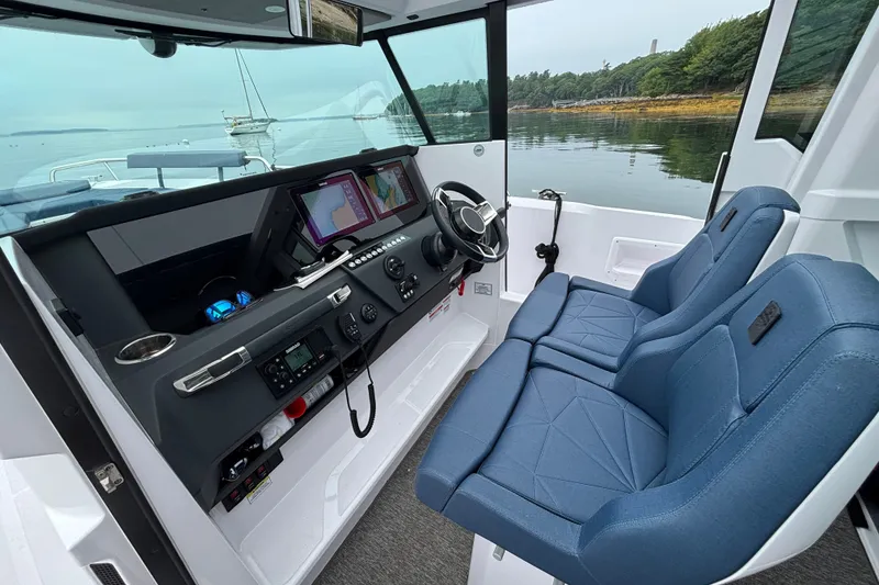 Slide: The Image of 2025 Axopar 29 XC Cross Cabin interior with modern dashboard and blue seating. - 12
