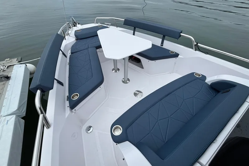 Slide: The Image of 2025 Axopar 29 XC Cross Cabin boat with blue seating and white table on calm water. - 38