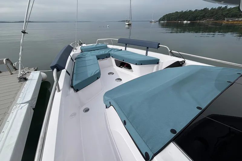 Slide: The Image of 2025 Axopar 29 XC Cross Cabin boat with blue seating, docked on calm water. - 21