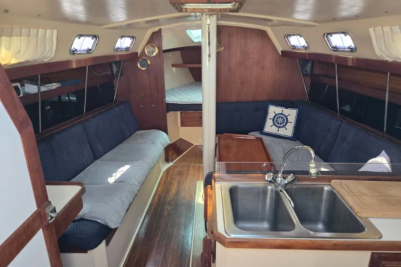 Slide: The Image of Interior of a 1989 Catalina 34 sailboat with cozy seating and a compact kitchen area. - 1