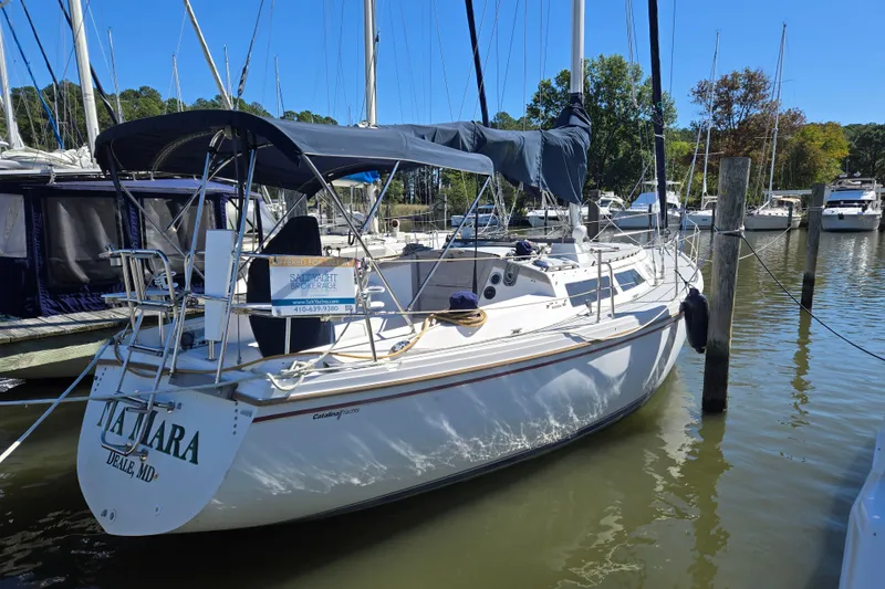 Slide: The Image of 1989 Catalina 34 sailboat docked in a marina, featuring a blue canopy and white hull. - 37