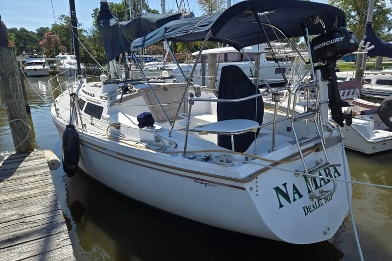 Slide: The Image of 1989 Catalina 34 sailboat docked, featuring a Mercury outboard motor and covered cockpit. - 35