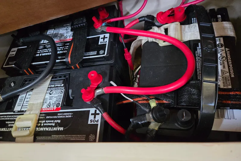 Slide: The Image of Battery compartment of a 1989 Catalina 34 sailboat with red cables and safety warnings. - 33